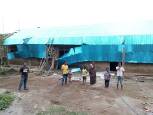 Foto: Beberapa warga dan murid SDN Wairpu'at sedang berdiri di halaman SD. Tampak di belakang adalah bangunan baru dengan atap seng yang rusak